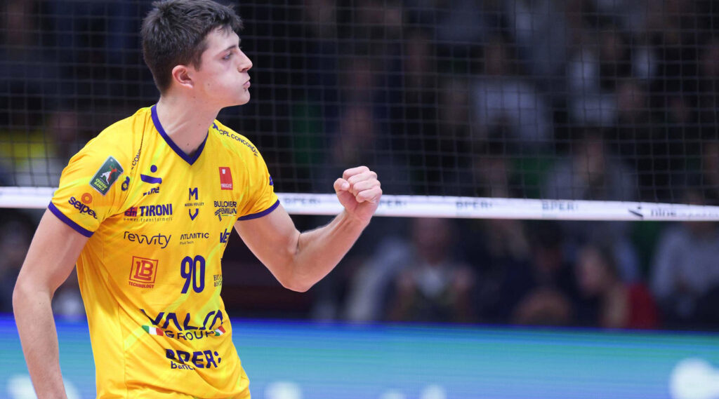 Giocatore del Modena Volley stringe il pugno con soddisfazione. rete sullo sfondo.